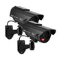 Black solar-powered dummy CCTV dome camera with flashing red LED light, suitable for indoor and outdoor security, with warning sticker.