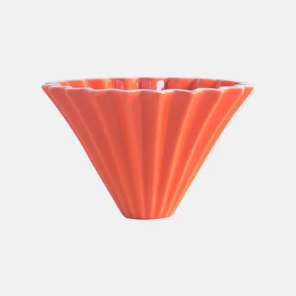 Orange ceramic hand brewing coffee dripper with origami flower shape, pour-over coffee maker and filter cup for fresh drip coffee.