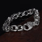 Stainless steel punk skull bracelet with bold design, featuring metallic links and skull accents, on a neutral background.