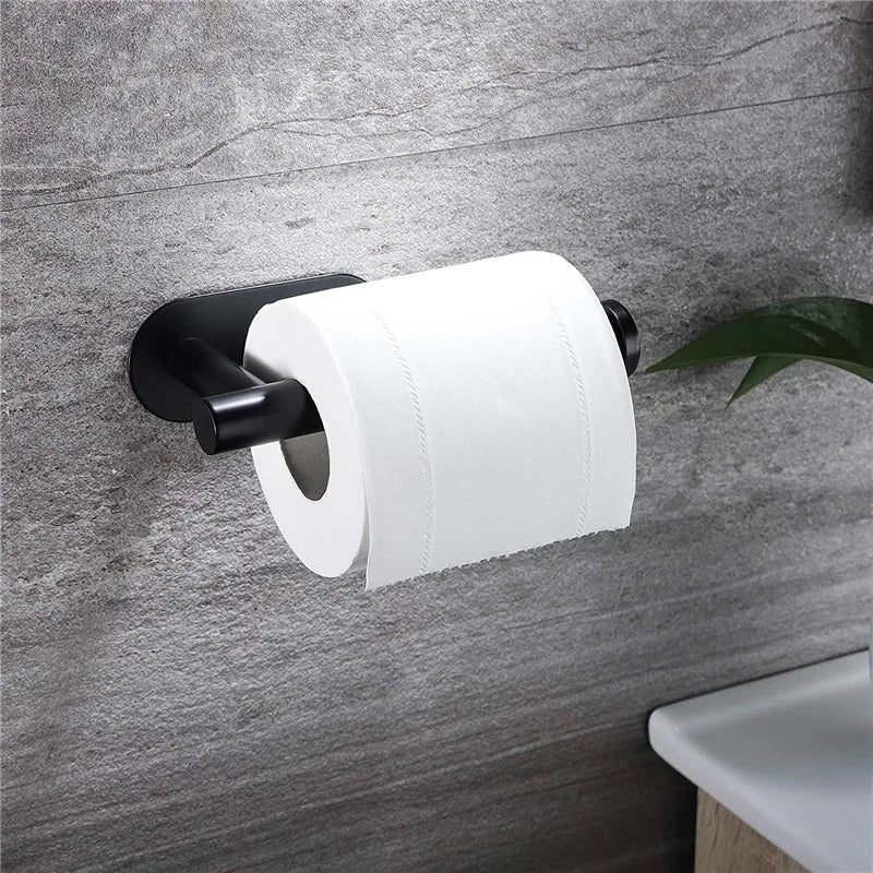 White kitchen paper towel holder with adhesive tissue hanger and toilet roll dispenser mounted on a bathroom cabinet.