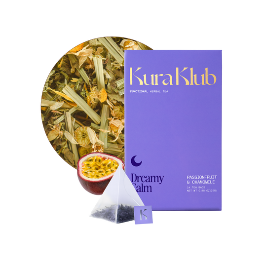 Chamomile and passionfruit tea from Kura Klub in a clear glass teacup with tea leaves and a passionfruit slice on a white background.