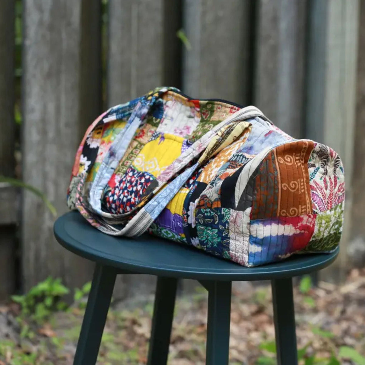 Patchwork quilted duffle bag by Darn Good Yarn, featuring colorful fabric patchwork and sturdy handles for travel or daily use.