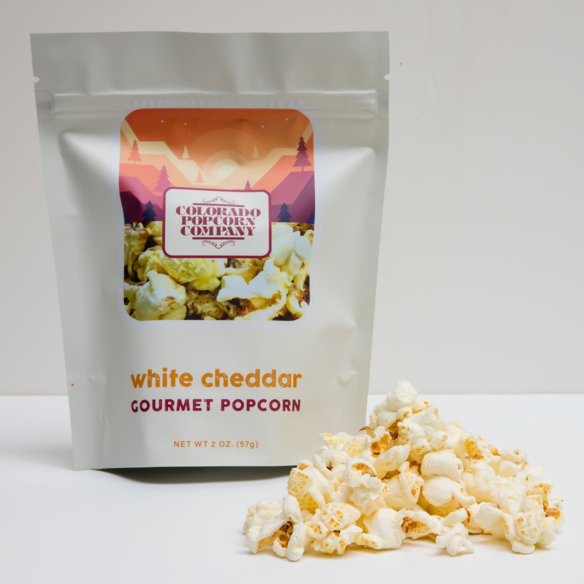 White cheddar popcorn from Colorado Popcorn Company in a 2 oz bag, showing crispy white cheddar-coated popcorn pieces.