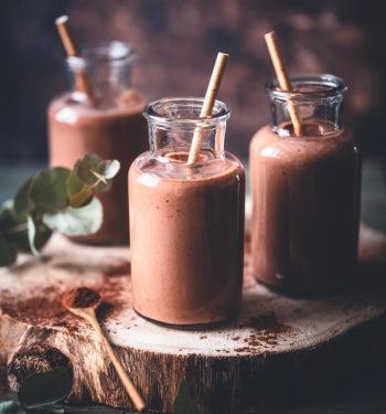 AmBari Nutrition hot chocolate drink in a mug with creamy cocoa, topped with whipped cream and cocoa powder.