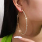 Large stainless steel women's rhinestone hoop earrings with gold finish, featuring sparkling bling design and bold hoop style.