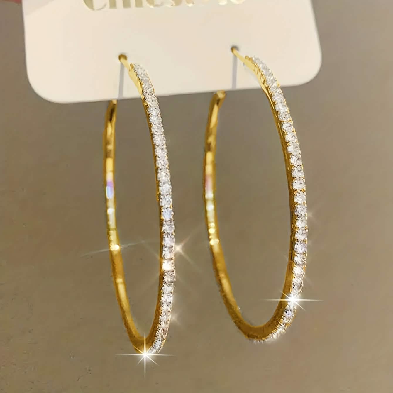 Large stainless steel gold hoop earrings for women with rhinestone embellishments, featuring bold bling design.