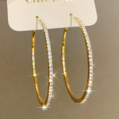 Large stainless steel gold hoop earrings for women with rhinestone embellishments, featuring bold bling design.