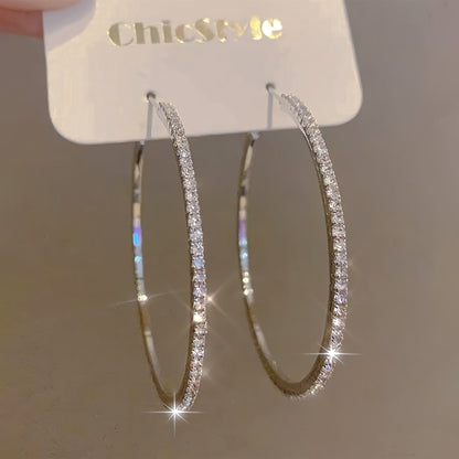 Large gold stainless steel women's rhinestone hoop earrings with sparkling bling design, showcasing their bold, elegant style.