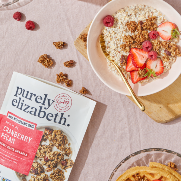 Purely Elizabeth Cranberry Pecan Ancient Grain Granola in a bowl with cranberries and pecans, showcasing crunchy texture and natural ingredients.