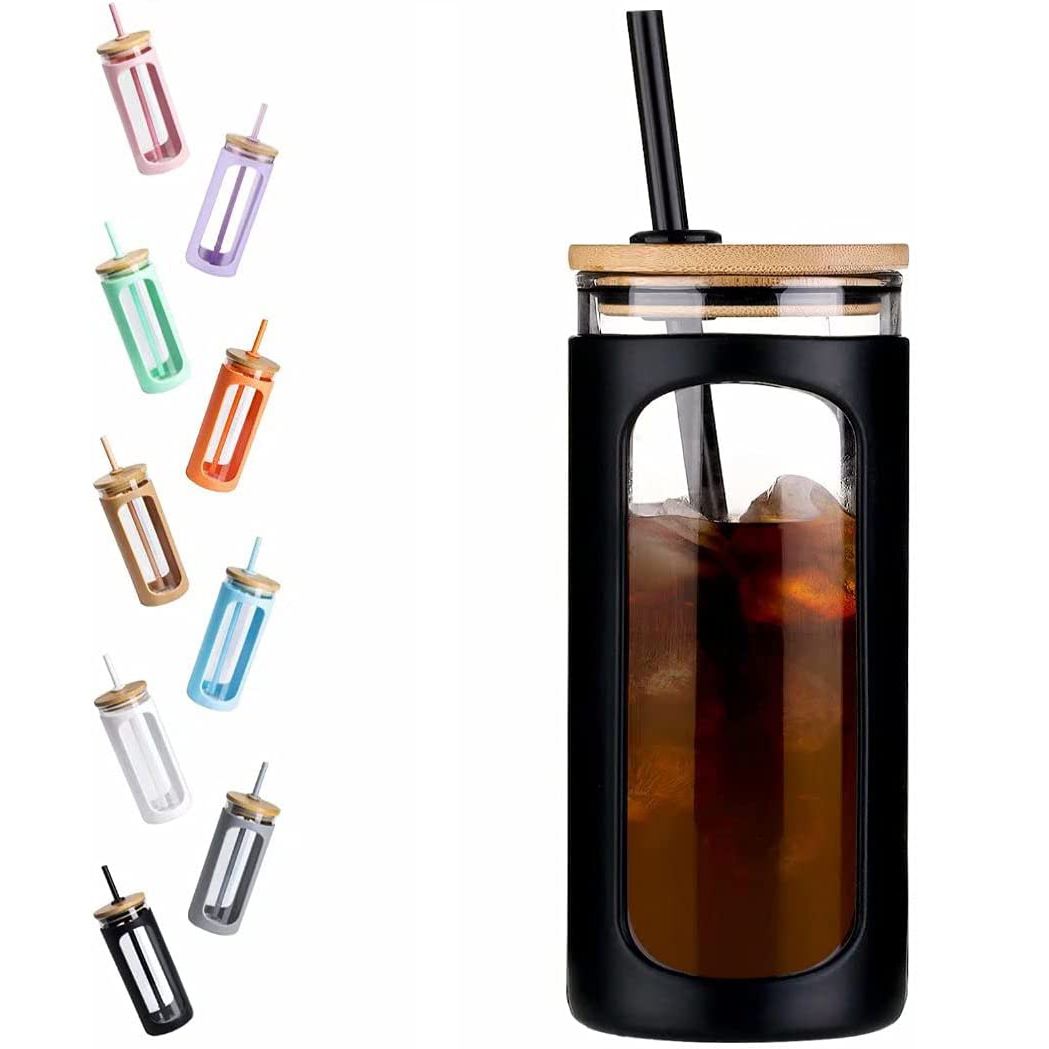Clear glass water tumbler with silicone bamboo lid and reusable straw, ideal for iced coffee and cold beverages.