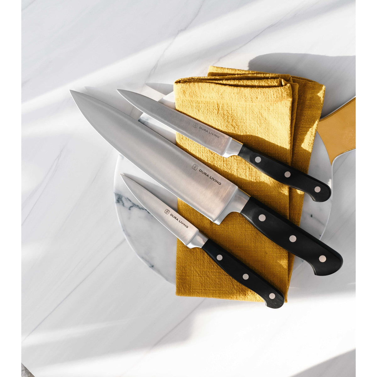 Dura Living Superior 4-Piece Kitchen Knife Set with black handles, including chef’s, paring, bread, and utility knives on a wooden surface.