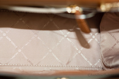 Michael Kors Carmen Signature Brown Satchel showing textured leather, double handles, and gold-tone hardware for stylish carry.