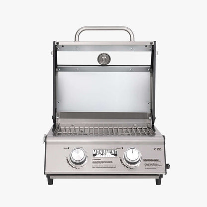 Stainless G22 Monument Grills tabletop propane gas grill on a kitchen countertop with lid closed, compact outdoor cooking appliance