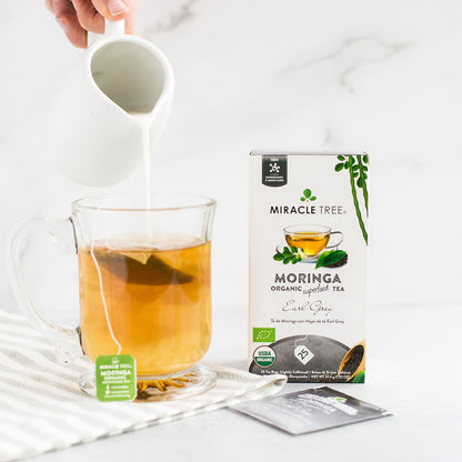 Organic Moringa Earl Grey Herbal Tea by Miracle Tree, low caffeine herbal tea with a tea bag and tea leaves in a cup.