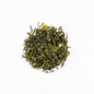 Organic Ganesha Green Tea from Nepal Tea, fresh green tea leaves in a traditional tea setup, highlighting natural and organic qualities.