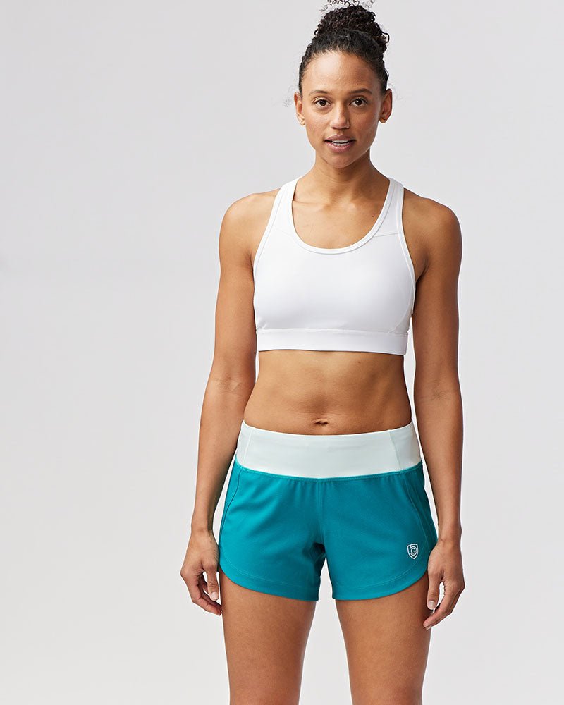Black Excel Women's Workout Shorts from Goal Five, designed for training, shown on a woman with a close-up view of the shorts.