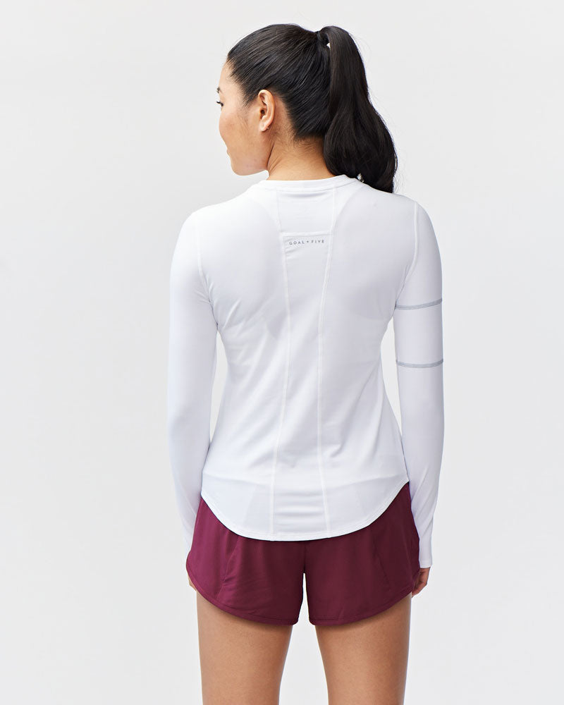 White women's long-sleeve workout top by Goal Five, designed for training and active wear, shown on a model.