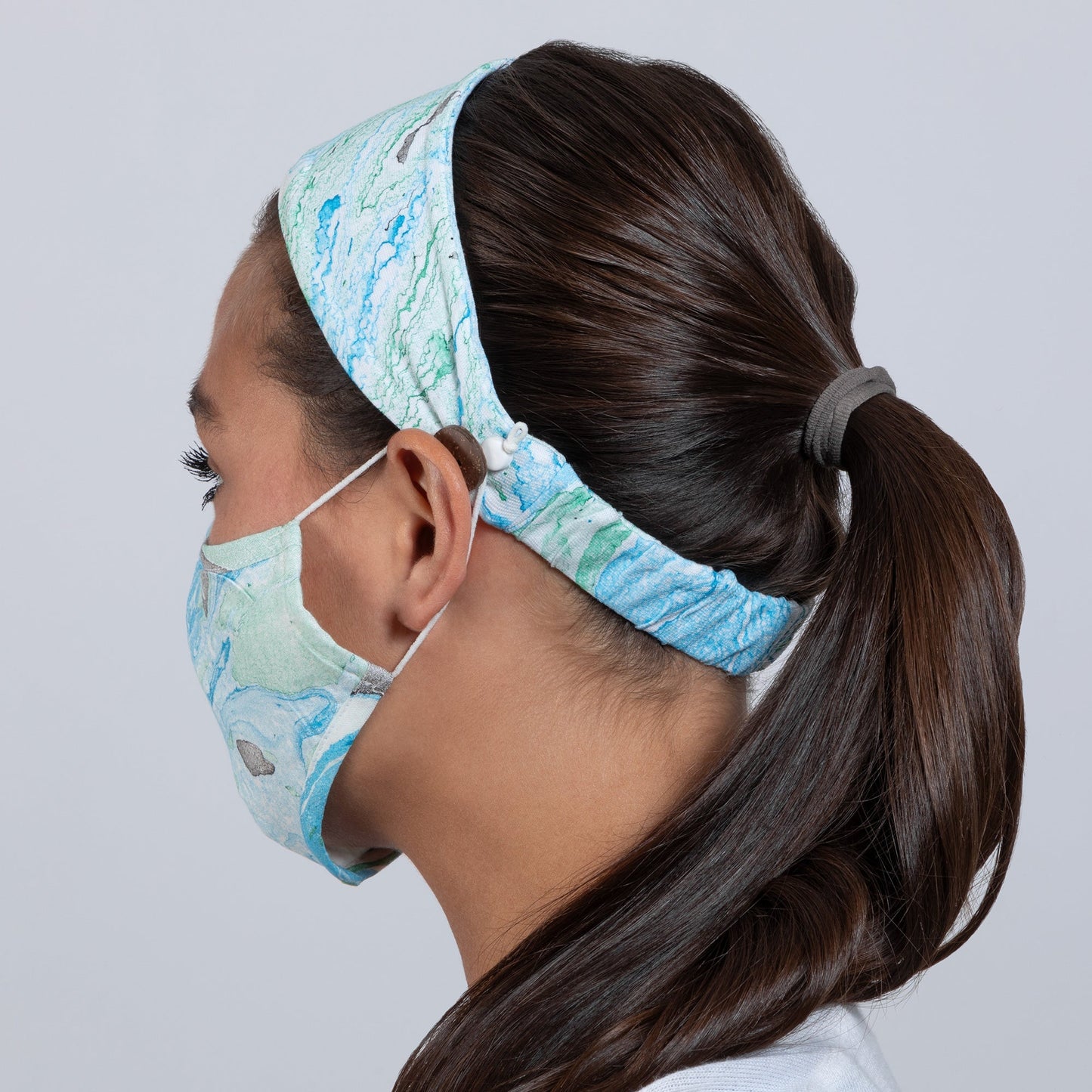 Green and blue marble-patterned face mask and matching headband from GreaterGood, made of soft fabric for comfortable wear.