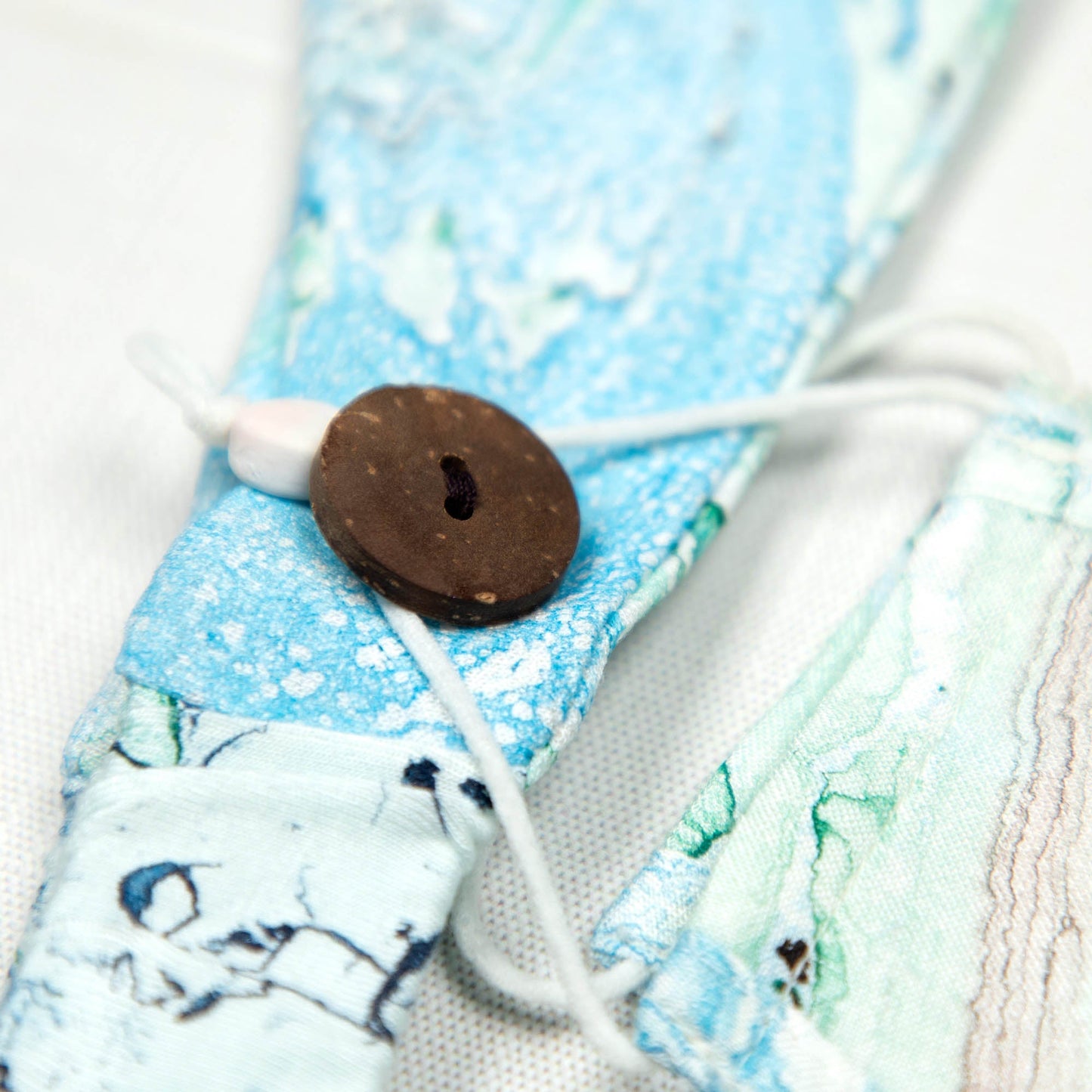 GreaterGood Marbleous color face mask and headband set with green and blue marbled design, made from soft, breathable fabric.
