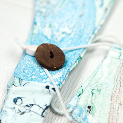 GreaterGood Marbleous color face mask and headband set with green and blue marbled design, made from soft, breathable fabric.