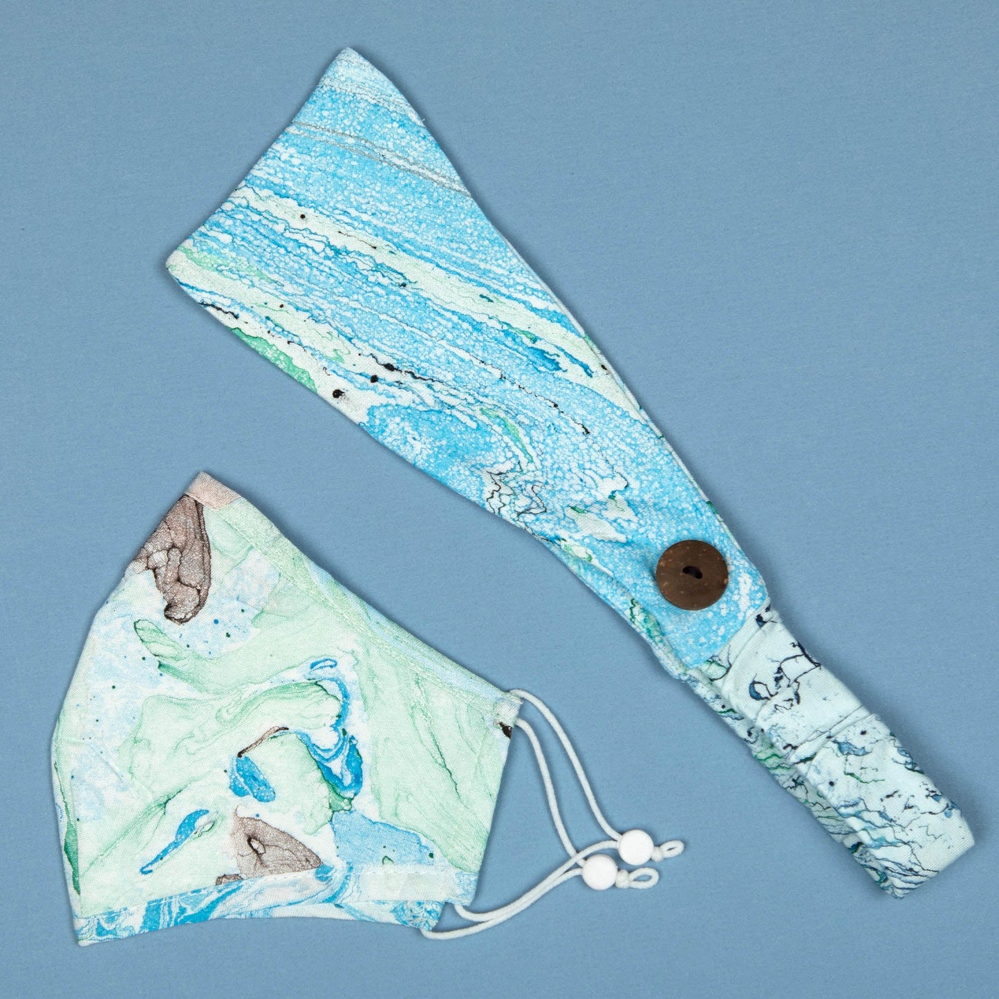 Green and blue Marbleous color face mask with matching headband from GreaterGood, made of soft, breathable fabric.