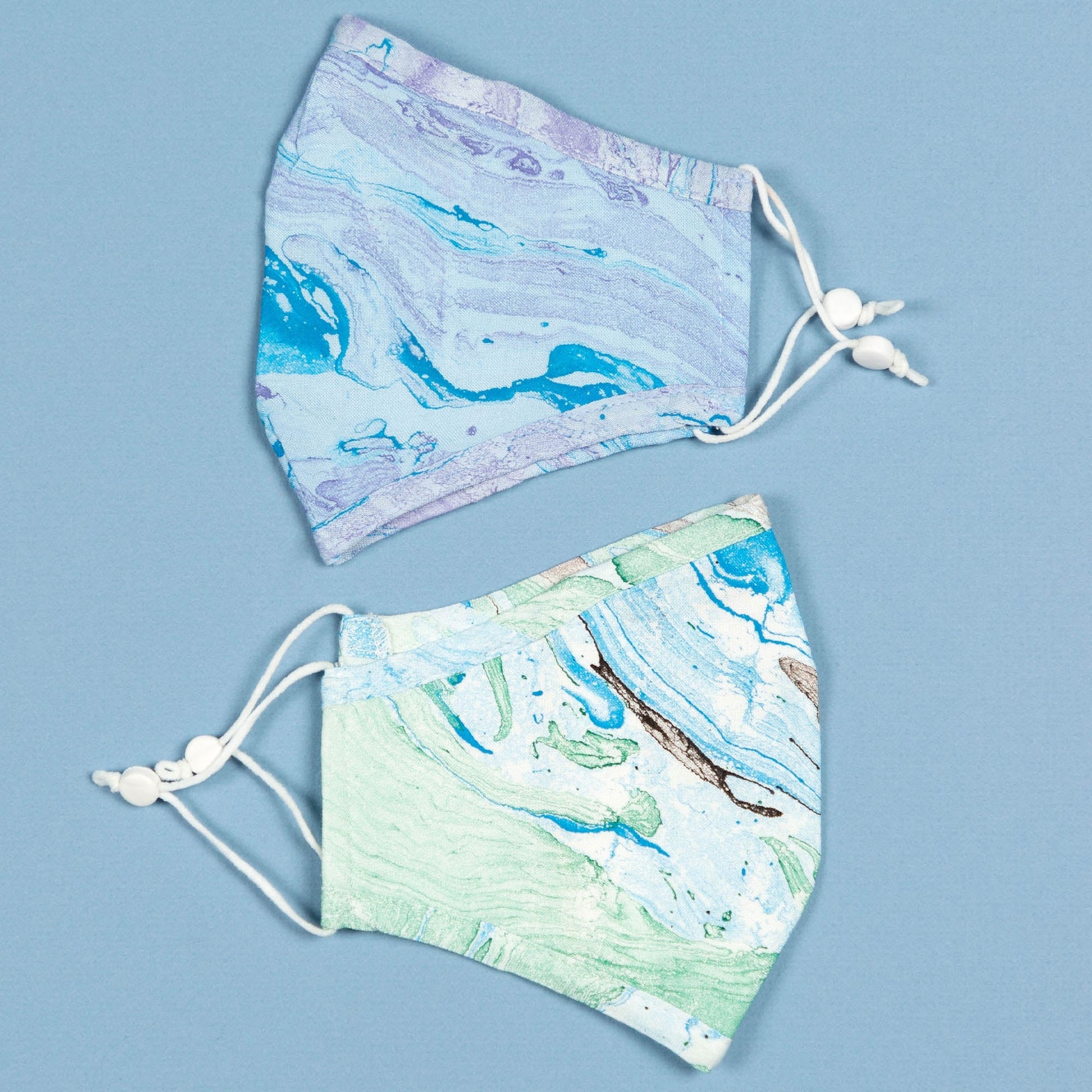 Green and blue marbleized face mask with matching headband from GreaterGood, made of soft, breathable fabric for comfortable wear.