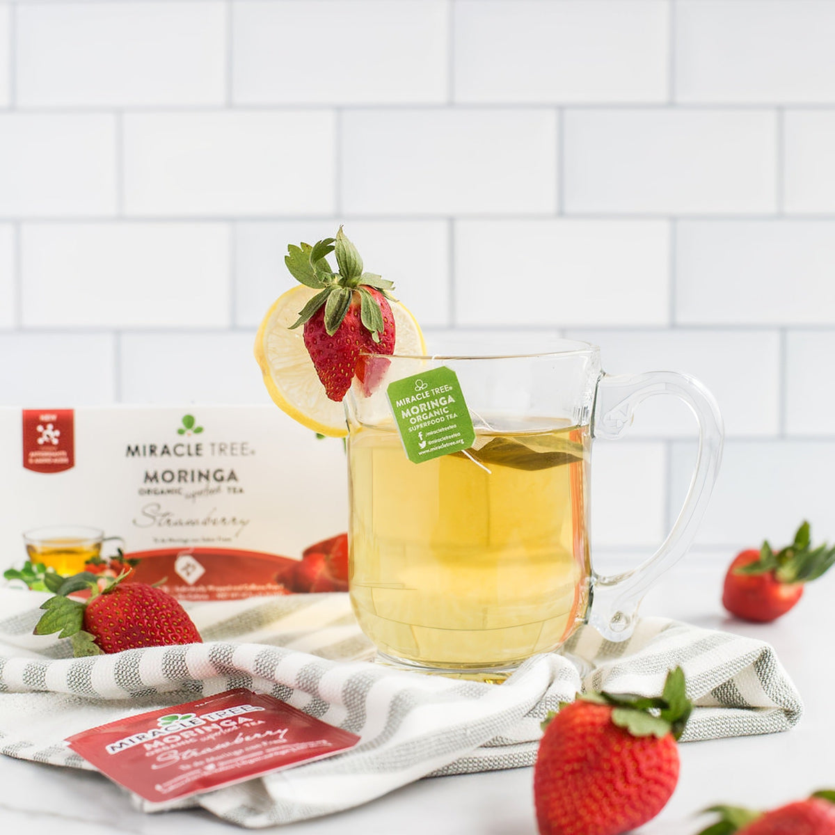 Organic Moringa Strawberry Herbal Tea by Miracle Tree in a clear tea bag, ready for brewing, with dried moringa leaves and strawberry pieces.