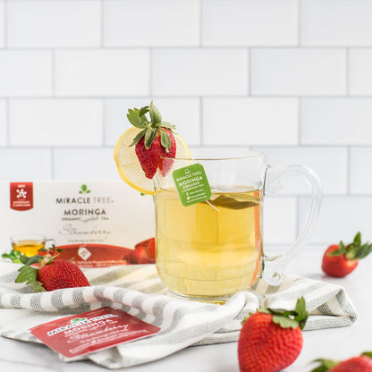 Organic Moringa Strawberry Herbal Tea by Miracle Tree in a clear tea bag, ready for brewing, with dried moringa leaves and strawberry pieces.