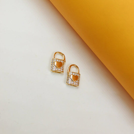 MIA Jewelry Lock Heart Huggies earrings in gold-tone metal with small heart charms, close-up view of the jewelry.