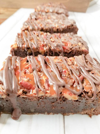 Chocolate turtle brownies from Let's Get Baked Artisan Desserts, featuring rich brownies topped with caramel, pecans, and chocolate.