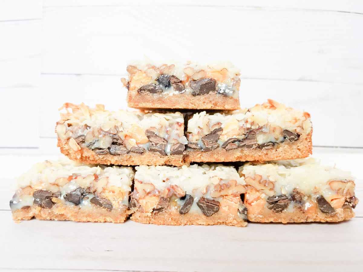 Let's Get Baked Artisan Desserts Magic Bars, layered cake and dessert bars with chocolate, caramel, and nut toppings.