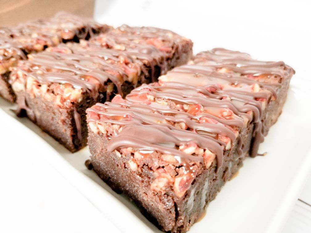 Chocolate turtle brownies from Let's Get Baked Artisan Desserts, featuring rich brownies topped with caramel, pecans, and chocolate.