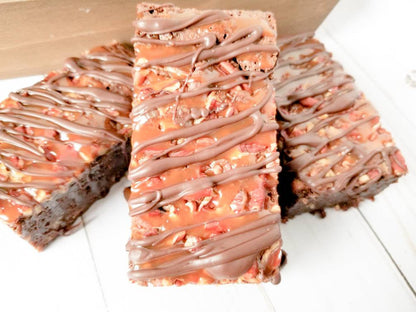 Turtle brownies from Let's Get Baked Artisan Desserts featuring rich chocolate cake with caramel and pecans, topped with chocolate.