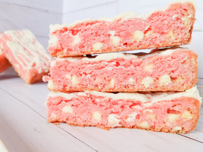 Strawberry blondies from Let's Get Baked Artisan Desserts, featuring layered cake bars with strawberry flavors and a golden finish.