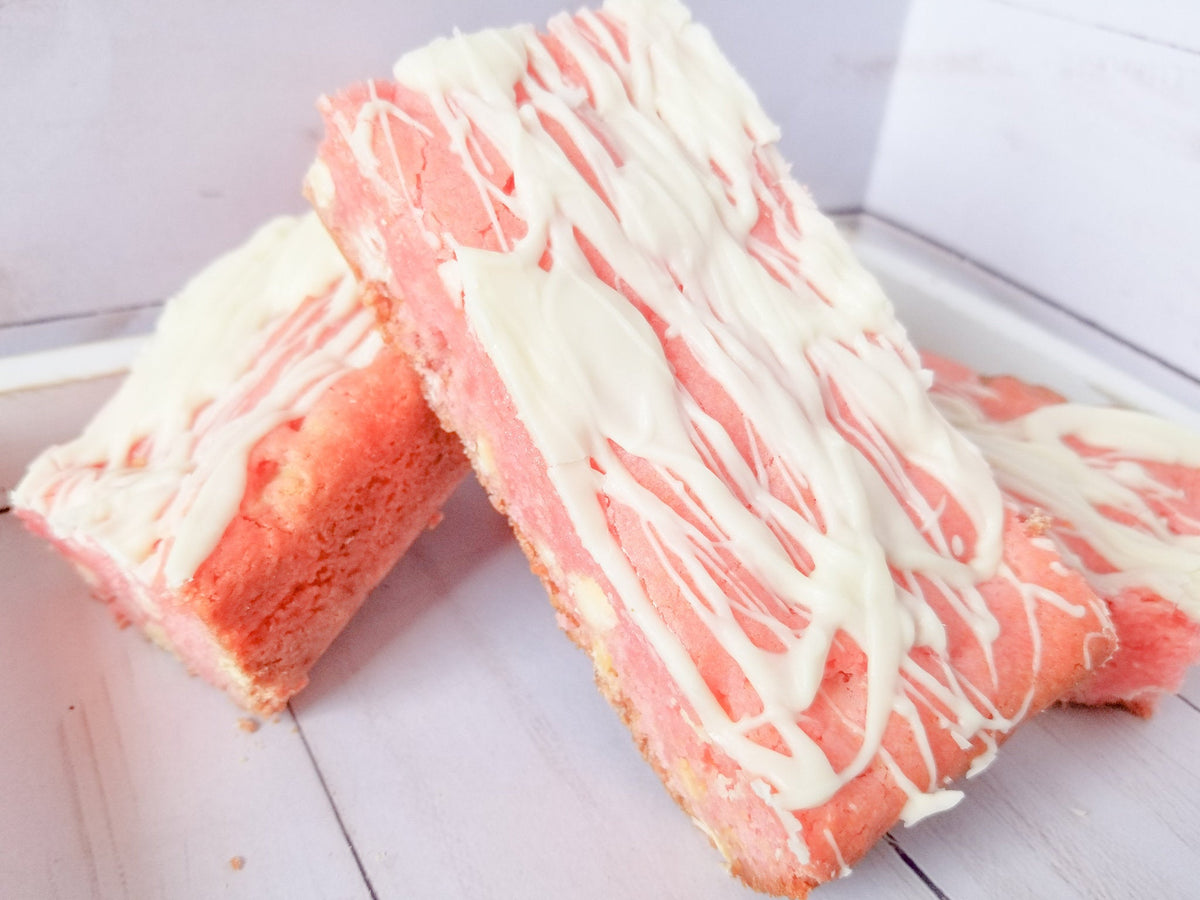 Strawberry blondies from Let's Get Baked Artisan Desserts, featuring golden cake bars with strawberry swirls and a moist texture.