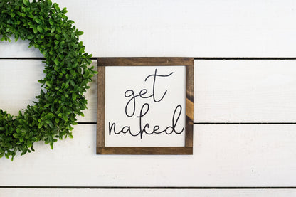 Square metal sign by The McGarvey Workshop with "Get Naked" text, featuring a bold black and white design for wall decoration.
