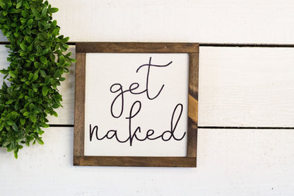 Square "Get Naked" sign by The McGarvey Workshop, featuring bold black text on a white background with a simple, modern design.
