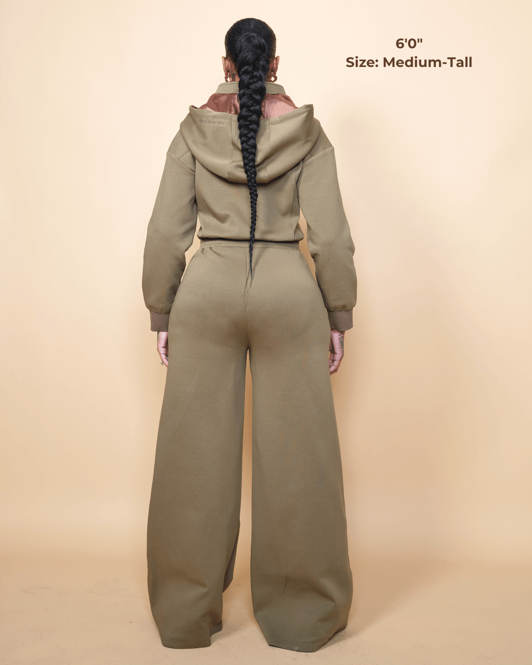 Green satin-lined jumpsuit by KINApparel, showing the front view with a fitted waist and long sleeves.