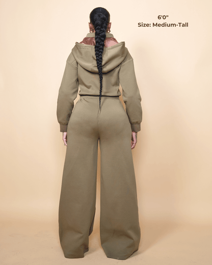 Green satin-lined jumpsuit by KINApparel, showing the front view with a fitted waist and long sleeves.