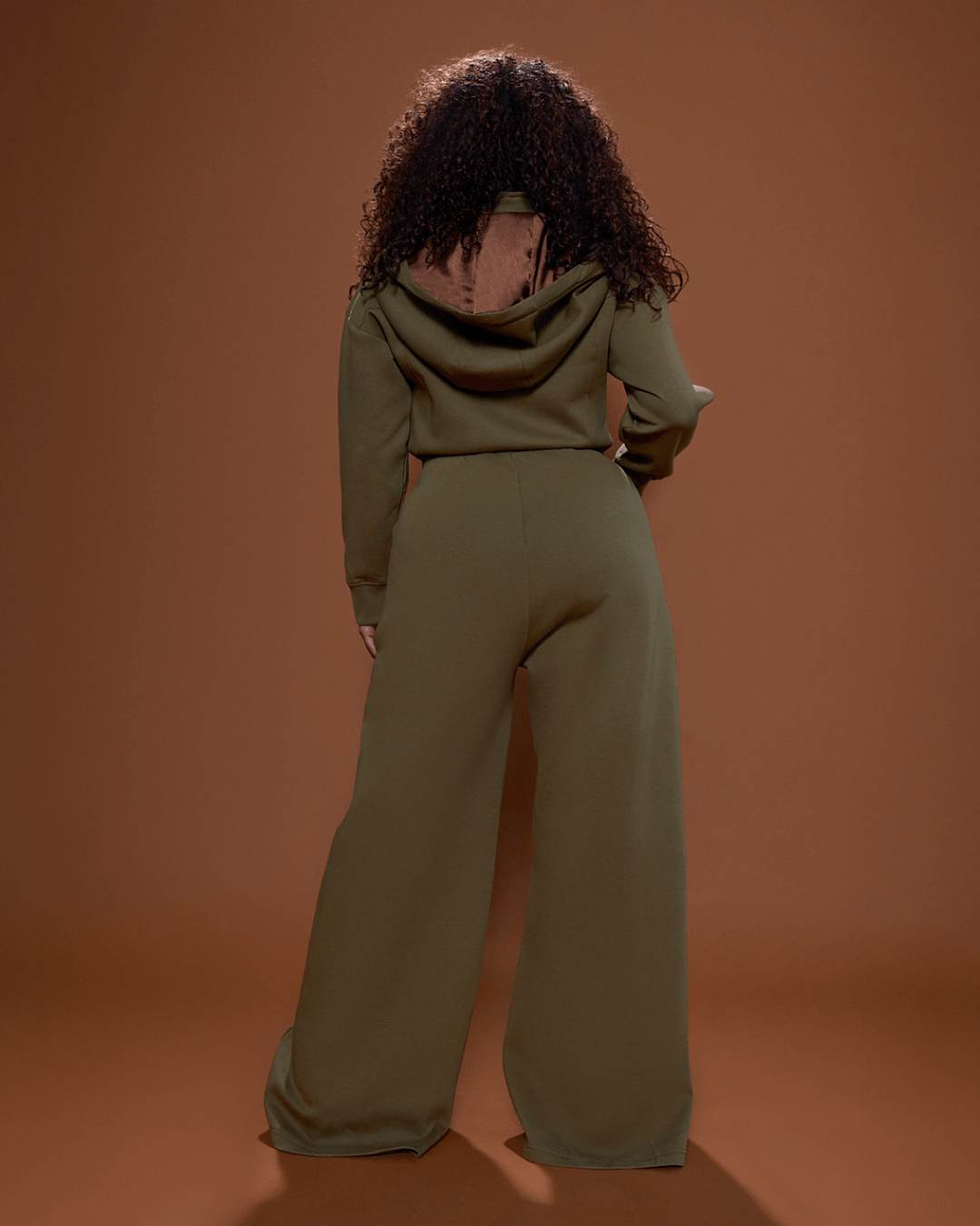 Green satin-lined jumpsuit by KINApparel, featuring a fitted design and long sleeves, shown on a mannequin.