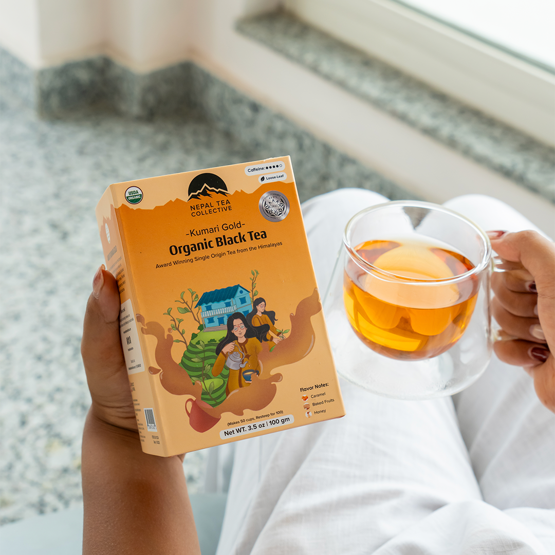 Organic Kumari Gold tea from Nepal Tea in a clear glass cup showing its rich golden brew and fresh tea leaves.