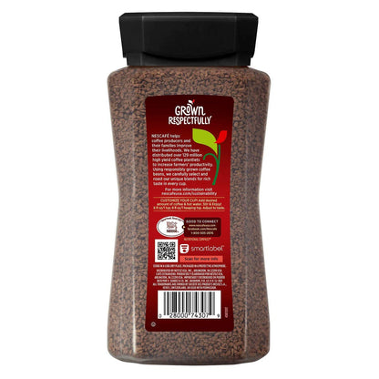 Cup of KupofK Coffee Nescafe Taster's Choice instant coffee in a clear glass mug with a spoon on a wooden table.