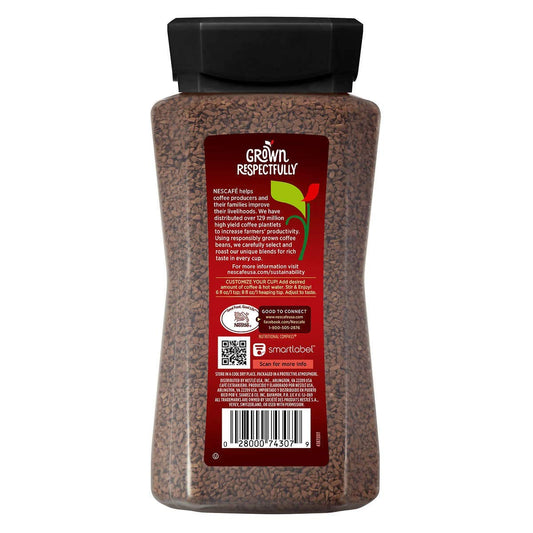 Cup of KupofK Coffee Nescafe Taster's Choice instant coffee in a clear glass mug with a spoon on a wooden table.