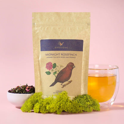 Green tea blend called Midnight Rosefinch from Birdsong Tea with jasmine and orange in a teacup on a saucer.