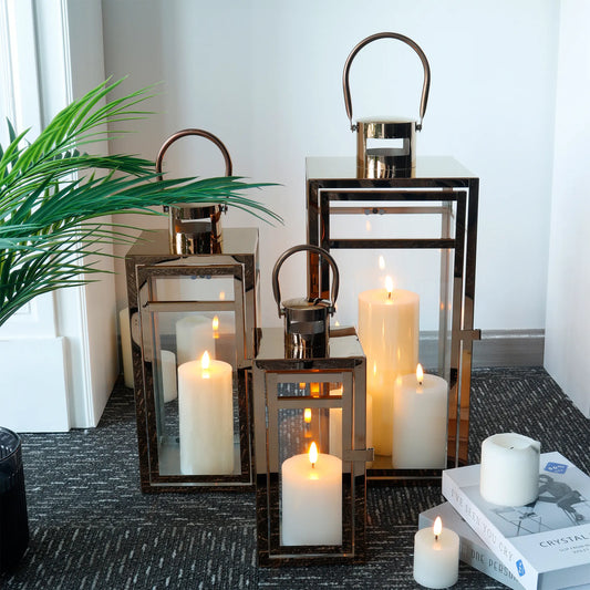 Set of three rose gold stainless steel outdoor candle lanterns in 12, 15, and 19-inch sizes, decorative JHY DESIGN candle holders.