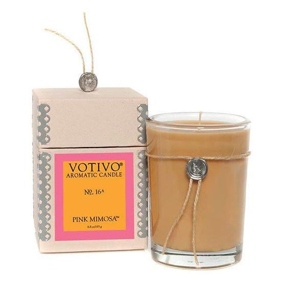 Pasteur Pharmacy Votivo Aromatic Candle Pink Mimosa 6.8oz burning with soft pink glow, showcasing elegant packaging and floral scent.