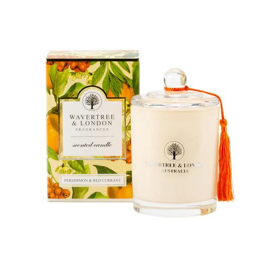 Wavertree & London Persimmon and Red Currant scented candle in a glass jar with a lit wick, showcasing warm autumn tones.