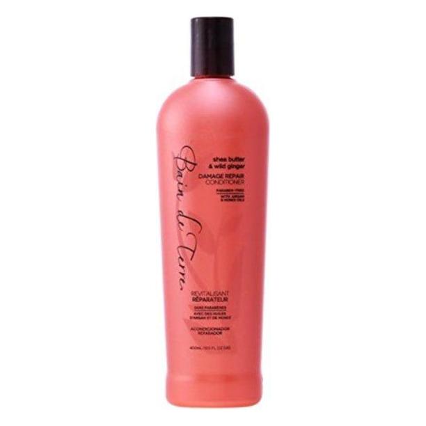 Bain De Terre Shea Butter & Wild Ginger Damage Repair Conditioner in 13.5 fl oz bottle, with conditioner poured into a shower setting