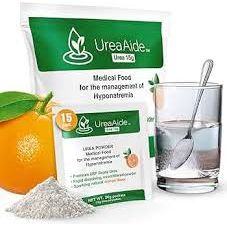 Fresh oranges on a table, with UreaAide Urea Supplement packets from Pasteur Pharmacy in the background