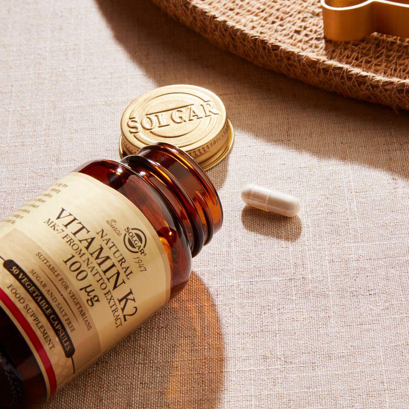 Solgar Vitamin K2 100 mcg supplement in 50 vegetable capsules, displayed in a clear container with label details.
